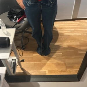 Mörkblå wide jeans med raka ben - Säljer ett par mörkblå jeans med bred passform och raka, vida ben. Klassisk femficksmodell med normal midja och dragkedja. Perfekta för dig som gillar en avslappnad och trendig look. Materialet är klassisk denim i bomull.