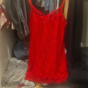 Röd spetsklänning med smala axelband - Snygg röd kortklänning/topp med smala axelband och v-ringad hals. Toppen har fina spetsdetaljer upptill och nertill som ger en romantisk vibe. 🌸Perfekt för dig som vill sticka ut med en färgstark look. Och dra all uppmärksamhet till dig🌸.💐💐💐 Materialet känns lätt och följsamt. Det är en topp men nästan som en väldigt kort klänning. Defekten du kan se är den på sista bilden då det är ett svart märke, men jag tror att det kanske kan gå bort? priset kan diskuteras cupcakes♡