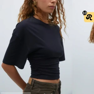 Svart croppad topp med rynkade sidor - Svart croppad topp från Monki med rynkade sidor som ger en snygg siluett. T-shirten har rund halsringning, korta ärmar och är tillverkad i mjuk bomull. Perfekt att styla med höga jeans eller kjol för en trendig look. ALDRIG ANVÄND! Helt ny❤️ köptes för 260kr!