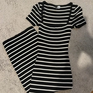 Randig klänning från H&M - Svart och vit ribbad klänning från H&M. Klänningen har korta ärmar, fyrkantig ringning och ränder. Materialet är stretchigt och sitter tight mot kroppen. Aldrig använd.