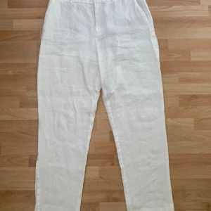 Vita linnebyxor från MNG, storlek 38 - Snygga och luftiga vita linnebyxor från MNG i storlek 38. Byxorna har raka ben, bälteshällor och klassisk midja. Perfekta för varma dagar när du vill ha en clean och fräsch look. Passar till både sneakers och sandaler.