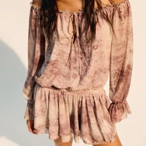 Klänning i bohostil - Superfin kortklänning i beige och bruna toner från Bershka. Klänningen har offshoulder-modell med långa ärmar, volangkant nertill och knytning vid halsen. Tunt, luftigt material med subtilt mönster och romantisk vibe. Helt ny💕