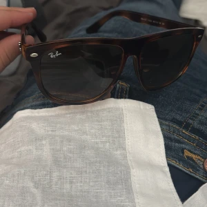 Ray-Ban Wayfarer brunmelerade solglasögon - Snygga Ray-Ban Wayfarer RB4147 med brunmelerad plastbåge och mörka glas. Klassisk och tidlös modell som ger en cool vibe till din outfit. Perfekta för soliga dagar och passar till det mesta. Modellnummer RB4147 syns på insidan av skalmen.