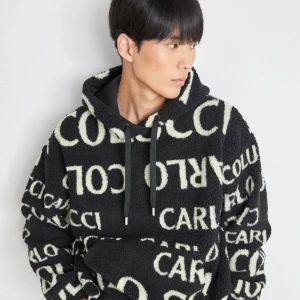 Svart hoodie Carlo Colucci med logga - Svart hoodie från Carlo Colucci i storlek S med stor vit logotyp tryckt över hela tröjan. Mjuk och fluffig känsla, perfekt för dig som gillar streetwear och vill sticka ut. Har huva och långa ärmar. Grym till jeans eller mjukisbyxor. Funkar för M också