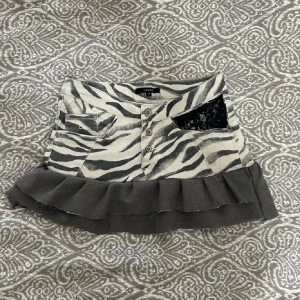 Zebramönstrad kortkjol med volang - As snygg zebramönstrad jeans kjol med volang. Köpt på Plick. Säljer då den inte kommer till användning. Sååå snygg  midjemått 37cm rakt över men stretshigt material 