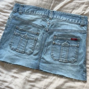 Ljusblå jeanskjol från Only Jeans - Säljer en ljusblå jeanskjol från Only Jeans i klassisk denim med rå kant nertill. Kjolen har två bakfickor med snygga detaljer och bälteshällor. Perfekt för dig som gillar en avslappnad och trendig stil.