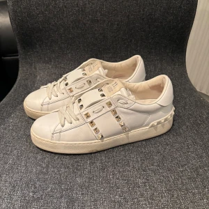 Valentino skor - Valentino ”open” i vit färg med guldiga nitar. Dam storlek 37. Fint skick, box, dustbag, kuvert medföljer. Väldigt eftertraktad modell. Skriv för mer bilder/info. Nypris ca 6500 :-❤️