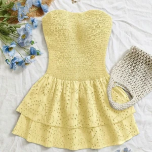 Gul axelbandslös volangklänning - Supersöt gul kortklänning med smockad överdel och axelbandslös design. Kjolen har två lager volanger och broderade hål för en extra somrig vibe. Perfekt för varma dagar när du vill sticka ut lite extra. Köpte den från shein men beställde 2st så behöver sälja en. Det är storlek M och beställde den för 200kr och den är aldrig använd.