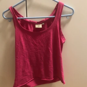 Rosa linnetopp från Tribute XS - Säljer en enkel och snygg rosa linnetopp från Tribute i storlek XS. Toppen har breda axelband och rundad halsringning, perfekt för varma dagar. Tillverkad i mjuk bomull som känns skön mot huden. Passar dig som gillar en basic men färgstark stil.