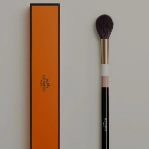Hermès sminkborste med ask - Lyxig sminkborste från Hermès med svart och rosa handtag, guldfärgad metall och mjuka, mörka borst. Kommer i klassisk orange Hermès-ask. Perfekt för att applicera puder, rouge eller highlighter.