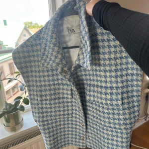 Rutig blå och vit väst från Zara - Snygg väst från Zara i blått och vitt rutigt mönster. Västen har krage, knappar framtill och två fickor. Perfekt för att lyfta din outfit med en cool och trendig touch.