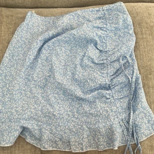 Blommig blå kjol med dragkedja - Säljer denna ljusblåa kjol men vita blommor på i storlek Xs. Knappt använd💕
