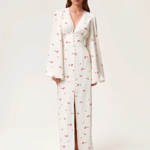 Vit långklänning adorre!😍 - Superfin långklänning i vit med små röda blommor, markerad midja och v-ringning. Klänningen har långa puffärmar och knappar framtill hela vägen ner. Perfekt för sommarens alla tillfällen och ger en romantisk vibe.