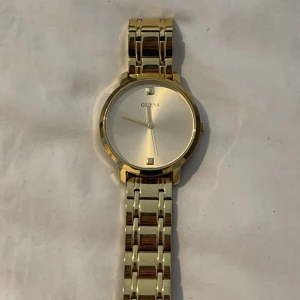 Guldig Guess Klocka MINI NOVA - Stilren klocka från Guess i modellen MINI NOVA med guldfärgat armband i rostfritt stål. Klockan har en rund urtavla i guld och minimalistisk design med diskreta markeringar. Perfekt accessoar för att lyfta din outfit. Orginal pris: 1695kr på zalando