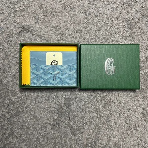 Ljusblå korthållare från G|oyard - Säljer en snygg ljusblå korthållare från G|oyard med deras ikoniska mönster. Korthållaren har flera fack för kort och är tillverkad i skinn med tryckt logga. Perfekt accessoar för dig som vill ha något stilrent och exklusivt. Kommer med tagg