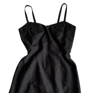 Svart kort klänning med paljettbroderi - Svart kort klänning med smala axelband och dekorativa paljettbroderier vid bysten. Klänningen har en figurnära passform och är perfekt för dig som vill ha en stilren men ändå detaljrik look.