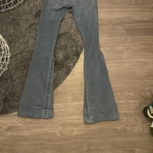 Blå low rise flare jeans från True Religion - Säljer ett par blå jeans från True Religion, modell Joey Low Rise Flare.  Storlek 23.Byxorna har låg midja och utsvängda. Två till 3 gånger andvända väldigt bra skick, säljer på grund av ingen andvänding❤️💕