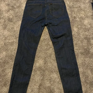 Mörkblå jeans från Lee - Säljer ett par klassiska mörkblå jeans från Lee med raka ben och normal passform. Jeansen har två bakfickor och Lee-logga på bakre linningen. Perfekta för dig som gillar en tidlös stil. Pris går att diskuteras 