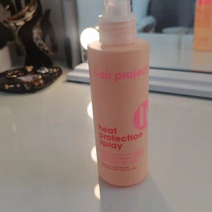 Heat Protection - Värmeskyddsspray från Hair Project i en ljusrosa plastflaska med spraymunstycke. Perfekt för att skydda håret mot värmeverktyg. Flaskan har rosa text och är smidig att ta med i väskan. Använd en gång.
