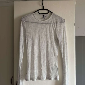 Vit ribbad långärmad tröja från H&M - Säljer en vit långärmad tröja från H&M. Tröjan är ribbad och har en tight passform.