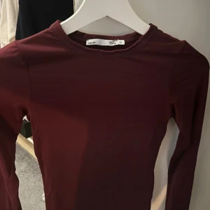 Vinröd långärmad topp från 157 - Säljer en enkel och stilren vinröd långärmad topp från 157. Toppen har rund halsringning och är tillverkad i ett mjukt bomullsmaterial. Perfekt att matcha med jeans eller kjol.