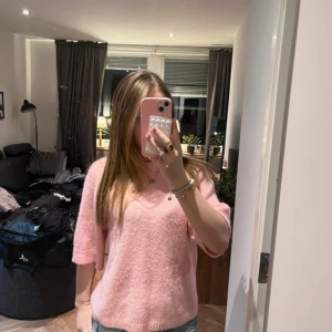 Ljusrosa stickad tröja med kort ärm - Säljer en supermjuk och fluffig ljusrosa stickad tröja med korta ärmar och rund hals. Perfekt för dig som vill ha en söt och bekväm look. Passar till både jeans och kjol. Snygg och enkel att styla!