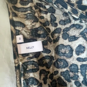 Leopardmönstrad topp från Nelly - Säljer en snygg leopardmönstrad topp från Nelly med långa ärmar och knytning framtill. Toppen har en figurnära passform och är perfekt för dig som vill sticka ut med ett djurmönster. Materialet känns lätt och bekvämt.