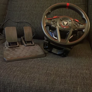 Thrustmaster T80 Racing Wheel med pedaler - Säljer en Thrustmaster T80 ratt och pedalset för racing-spel. Ratten är svart med röda detaljer och har flera knappar för olika funktioner. Pedalerna är också svarta och har halkskyddad bas. Perfekt för dig som vill ta bilspelandet till nästa nivå. Aldrig använt men kvitto finns inte kvar!