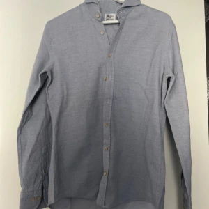 Ljusblå skjorta från Stenströms - Säljer en stilren ljusblå skjorta från Stenströms i slimline-modell. Skjortan har diskret mönster, klassisk krage och knappar framtill samt vid ärmslut. Tillverkad i tvåfaldigt super cotton för en mjuk och exklusiv känsla.  Storlek L men slim fit så passar bra på m