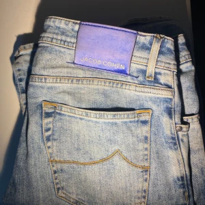 Ljusblå jeans från Jacob Cohën - Säljer ett par ljusblå jeans från Jacob Cohën med klassisk femficksdesign och kontrastsömmar. Jeansen har en patch i lila på linningen och en broderad J på myntfickan. Perfekta för dig som gillar stilrena och exklusiva jeans. De har endast en defekt under skrevet, men påverkar inte användning. Priset är ej hugget i sten! Tveka inte på att höra av dig vid frågor eller funderingar! Mvh Sixten 