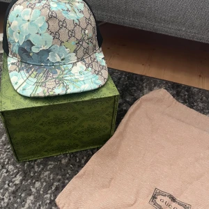 Gucci keps med blommigt mönster - Säljer min Gucci keps i storlek M som jag fick på min födelsedag i år. Säljer den för har märkt att den inte riktigt passar min stil och behöver pengar just nu. Priset är sänkt pågrund av att mina föräldrar tog kvittot till den så att jag inte skulle kunna sälja den +att en knapp Ibak inte går att knäppa med. Priset är ej hugget i sten!
