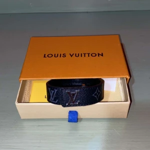  Louis Vuitton armband  - Säljer ett svart armband från Louis Vuitton med klassiskt LV-monogram i silver och grått. Bältet är gjort i skinn och har en stilren design. Perfekt accessoar för att lyfta din outfit. Pris kan  diskuteras!!