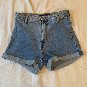 Blå jeansshorts  - Snygga blå jeansshorts från Bershka med hög midja och uppvikta benslut. Använd bara några gånger och fick shortsen begagnade. Katt finns i hemmet