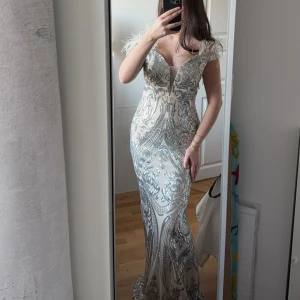 Silverglittrig långklänning med paljetter - Säljer en snygg långklänning i silver med glittriga paljetter. Klänningen har en figurnära passform, perfekt för bal eller fest.💕