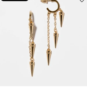 Guldörhängen med nitar - Säljer ett par coola guldörhängen med kedjor och konformade hängen. Örhängena har flera kedjor i olika längder och varje kedja avslutas med ett spetsigt konformat hänge. Perfekt för dig som vill sticka ut med din stil!