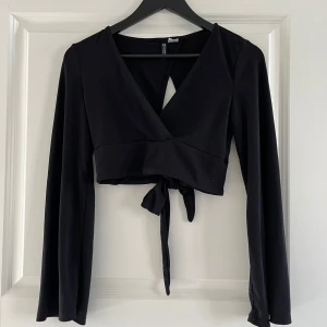 Svart omlottopp med öppen rygg - Svart omlott topp med öppen rygg och knytning i ryggen, även trumpetarmar🖤Storlek S från hm