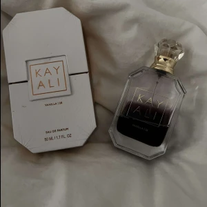 Kayali Vanilla | 28 Eau de Parfum - Exklusiv parfym från Kayali i doften Vanilla | 28. Flaskan är elegant med en kristalliknande kork och guldiga detaljer. Kommer i originalförpackning med vit och guldig design. Innehåller 50 ml Eau de Parfum.
