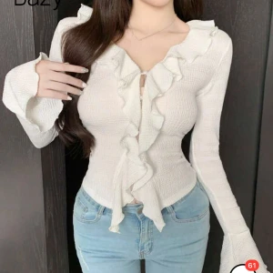 Vit volangtopp  - Trendig vit topp med volangdetaljer längs halsringningen och framtill. Aldrig använt 