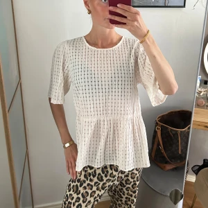 Blus - Säljer en söt creamfärgad blus med strukturmönster och volang nedtill. 