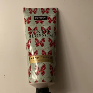 Winter Blossom Hand Cream med jasmin från Sence - Handkräm med jasmin-doft från Sence i en mintgrön tub dekorerad med röda fjärilar och guldiga detaljer. Perfekt att ha i väskan för återfuktade händer när som helst. Aldrig använd.