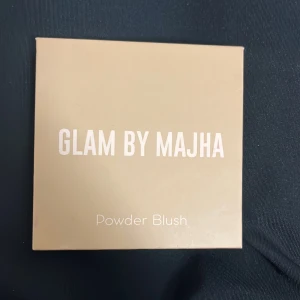Glam by Majha Powder Blush Barbie Girl - Säljer ett puderrouge från Glam by Majha i färgen Barbie Girl. Rouget är intensivt rosa och kommer i en fyrkantig beige förpackning. Perfekt för att ge kinderna en pop av färg. Innehåller 12g produkt.