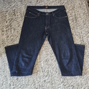 Mörkblå Lee jeans Daren Zip Fly W32 L34 - Säljer ett par klassiska mörkblå jeans från Lee, modell Daren Zip Fly. Jeansen har raka ben, fem fickor och snygga kontrastsömmar. Perfekta för dig som gillar en tidlös och enkel stil. Oanvända köpta från MQ för 1100kr. Mitt pris 499. Priset är inte satt i sten.
