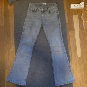 Ljusgråa bootcut jeans från Gina  - Säljer ett par ljusblå bootcut jeans från Gina. Jeansen har klassisk femficksdesign, knapp med logga och normal passform upptill som går ut i ett bootcut-snitt. 