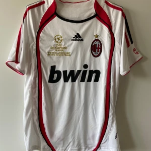AC Milan Kaká CL 2007 Tröja – Small - Legendarisk AC Milan-tröja från Champions League-säsongen 2006/2007 med Kaká #22 på ryggen – en hyllning till en av klubbens största stjärnor. Tröjan är i storlek Small och har klassisk design med CL-patch på ärmen och klubbens ikoniska färger. Passar perfekt för samlare, nostalgiker eller dig som älskar fotbollshistoria. Mycket fint skick – inga fläckar eller skador. En riktig ikon från Milans CL-triumf!