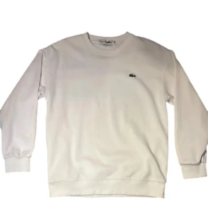 Vit sweatshirt från Lacoste - Säljer en stilren vit sweatshirt från Lacoste i storlek M, men sitter som S. Tröjan har en klassisk design med det ikoniska krokodilmärket på bröstet. Perfekt för en avslappnad och sportig look. Den är i mycket bra skick och passar till alla säsonger.