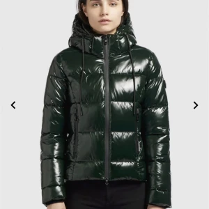 Khujo pufferjacka  - Grön glansig pufferjacka från Khujo. Perfekt till vintern.  Säljs då jag inte använder. Köpt för 1800kr. Storlek M men sitter som en S/xs