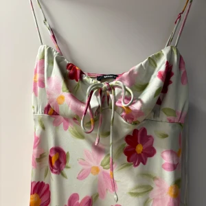 Blommig långklänning med knyt framtill - Blommig långklänning . Klänningen knyt framtill och justerbara band. Mindre skador på klänningen. 