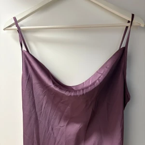 Lila långklänning med smala axelband - Säljer en lila långklänning med design rundad halsringning. Klänningen har justerbara band