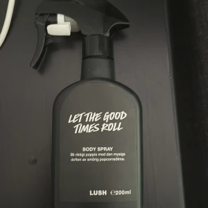 Let The Good Times Roll Body Spray från Lush - En svart sprayflaska med texten 'Let The Good Times Roll'. Kroppsspray med en mysig doft av smörig popcorn. Flaskan rymmer 200 ml. Ca halva kvar och säljs därav biligt