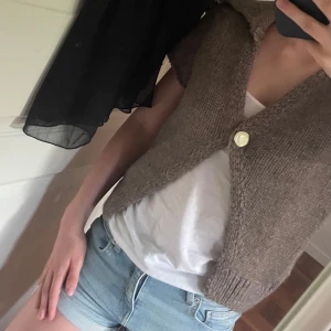 Beige stickad väst från Zara - Beige stickad väst från Zara med korta ärmar och stor krage. Västen har en stor vit knapp framtill och ribbade kanter. Använd en gång!